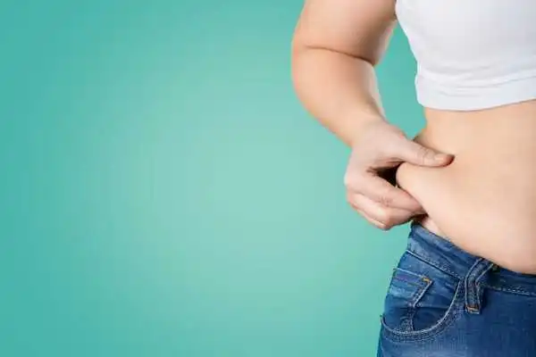 Image of woman pinching her love handles to show weight gain Wokingham