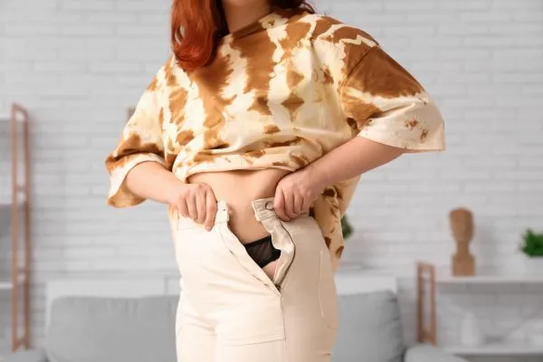 Image of woman trying to do her trousers up after pregnancy weight gain Wokingham